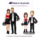 Custom couple bobbleheads: a man and woman in black outfits with helmets, standing side by side holding hands with a motorcycle vibe.