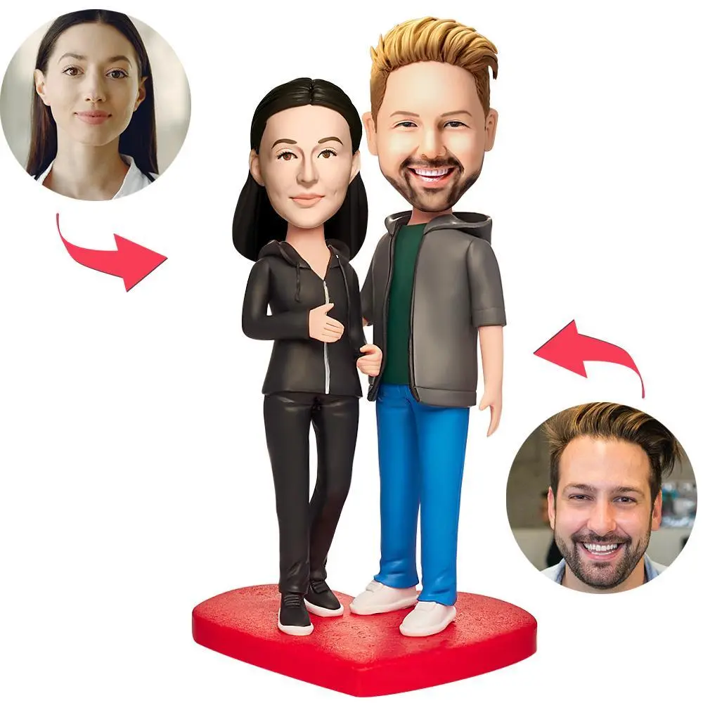 Custom couple bobbleheads on a red heart-shaped base with inset photos of the real people used for customization on each side.