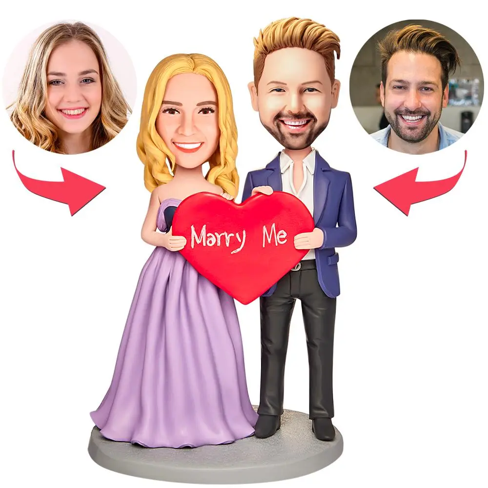 Cartoon couple wedding figurine holding a red heart that says 'Marry Me', with two circular headshots shown on either side.