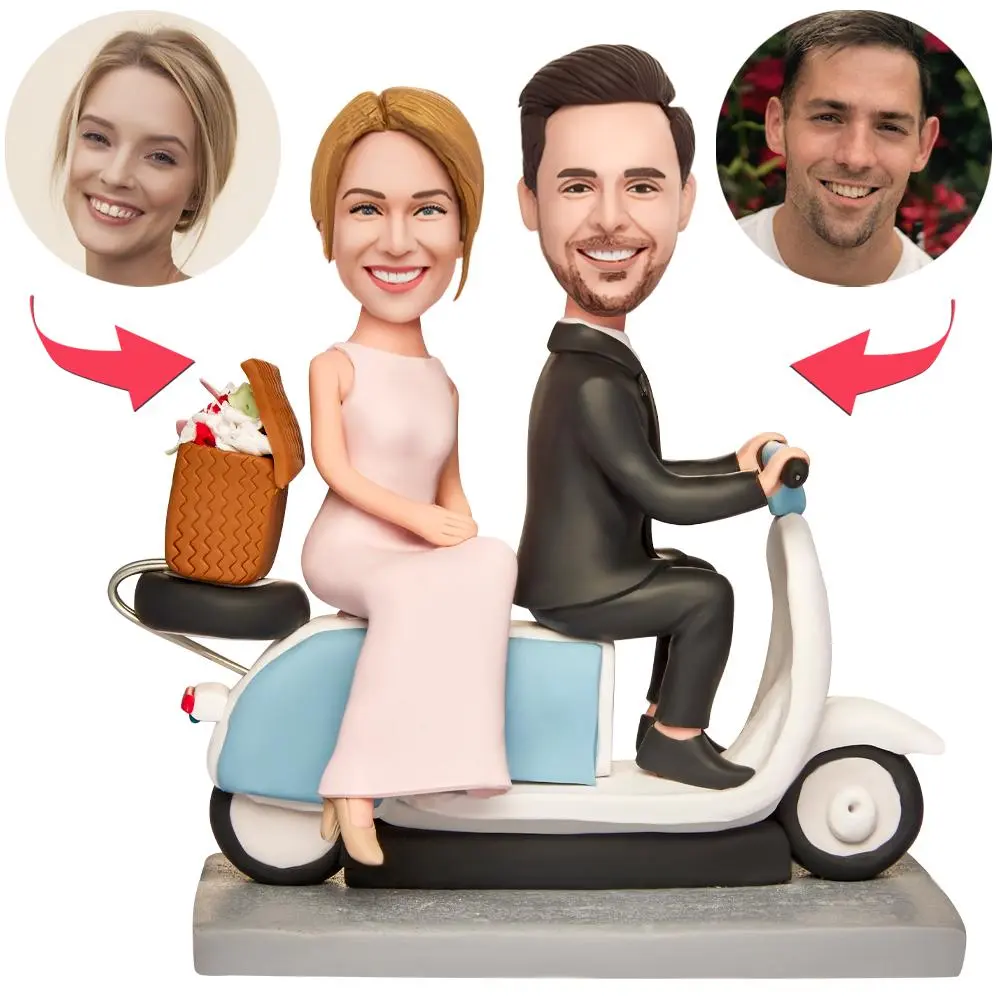 Caricature wedding cake topper: bride and groom ride a blue scooter with a gift basket on the back; circular portrait placeholders above indicate customizable faces.