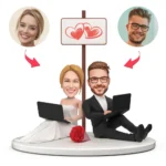 Wedding-themed cartoon couple with laptops, hearts on a sign above, sitting on a round pedestal with a red bouquet nearby.