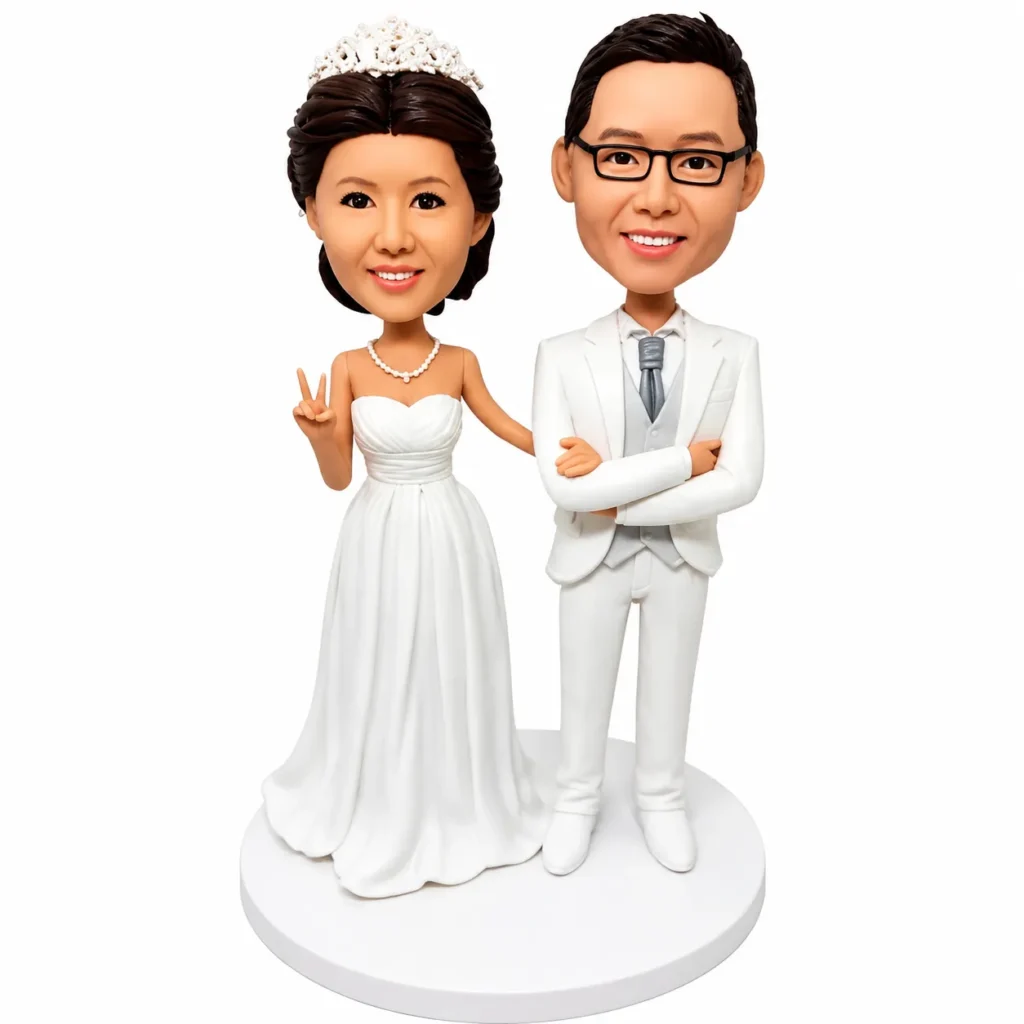 Wedding cake topper with a bride in a white gown and a groom in a white suit on a circular base, set against a white background