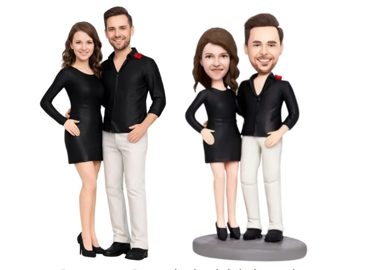 Two couples in black outfits posing together; real couple on the left and their caricature figurines on a pedestal on the right.
