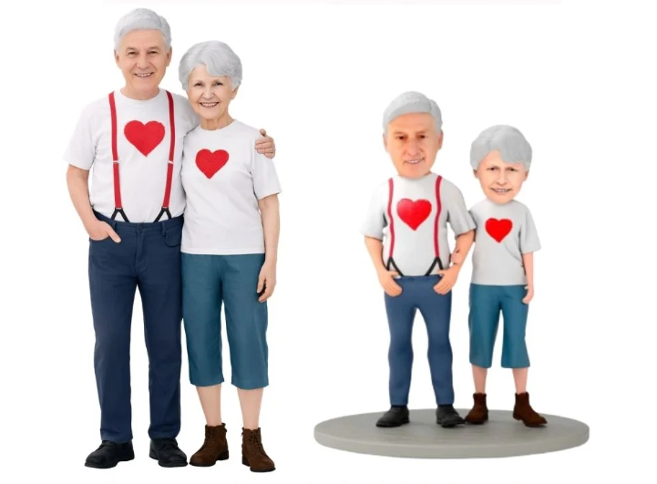 Elderly couple with matching white shirts and red hearts, standing with two smaller, same-outfit figurines on a round base.