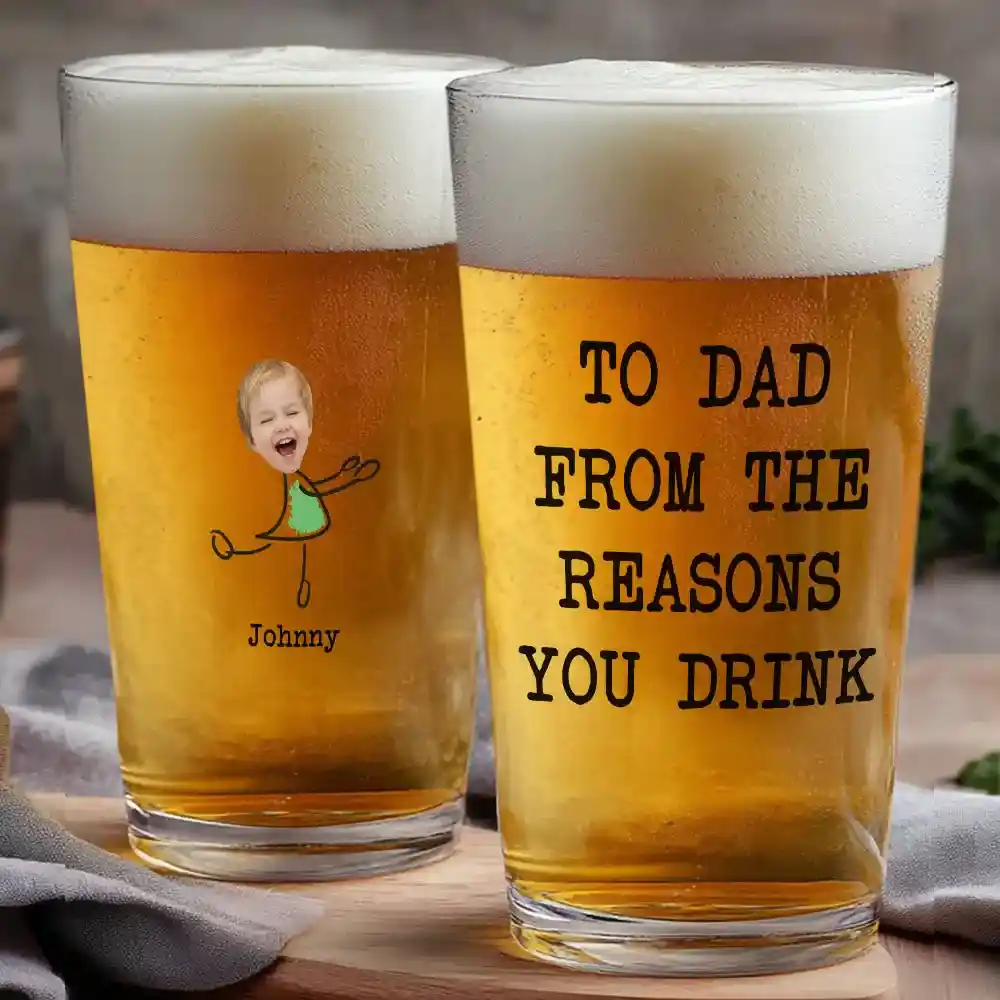 Two beer glasses with frothy tops; one features a child-like drawing and text, 'To Dad From The Reasons You Drink'.