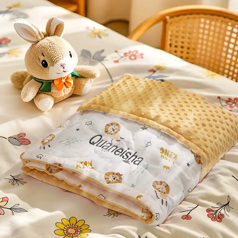Soft beige stuffed bunny on a bed beside a folded beige dotted blanket and a lion-pattern baby quilt.