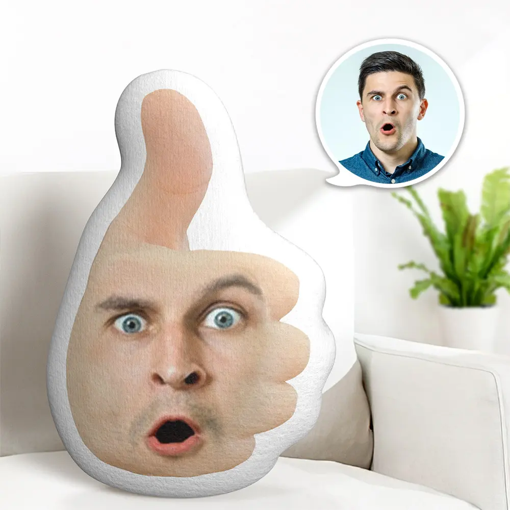 Oversized thumbs-up cushion with a surprised-face print on a white sofa; inset shows a man with wide eyes reacting.