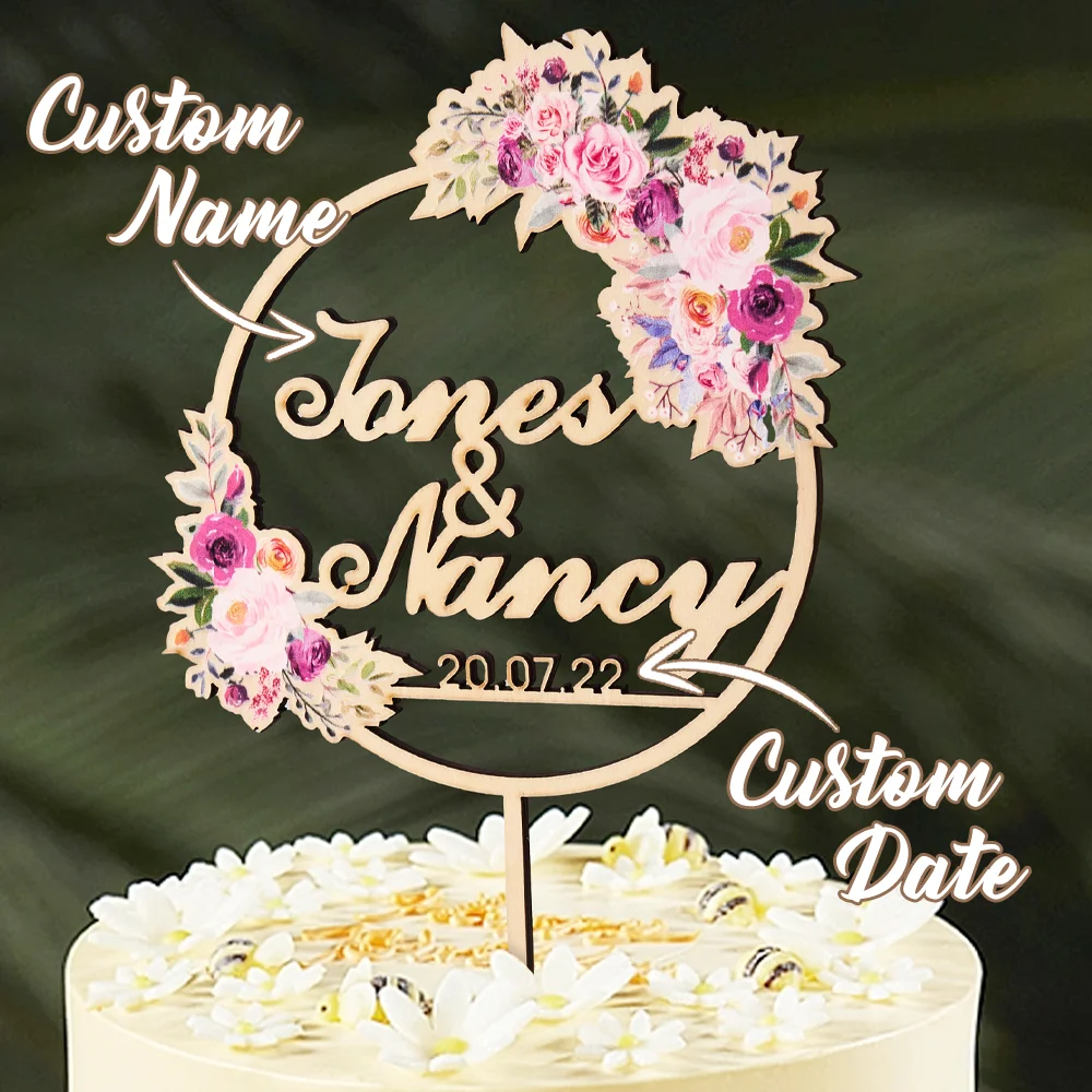 Wooden circular wedding cake topper with a floral wreath and the names 'Jones & Nancy' plus date 20.07.22.