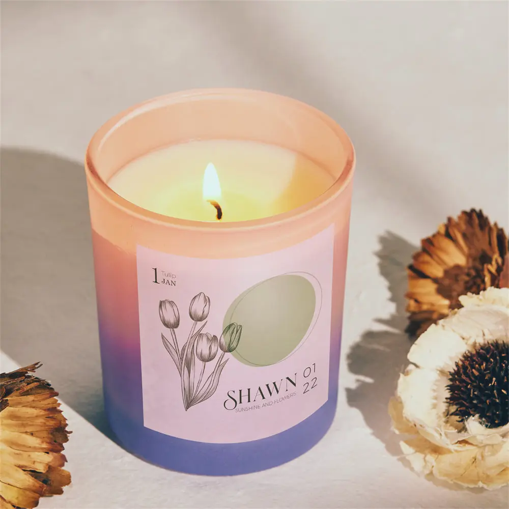 Pastel gradient candle (pink to purple) lit with a small flame, label features flowers and the brand name SHAWN.
