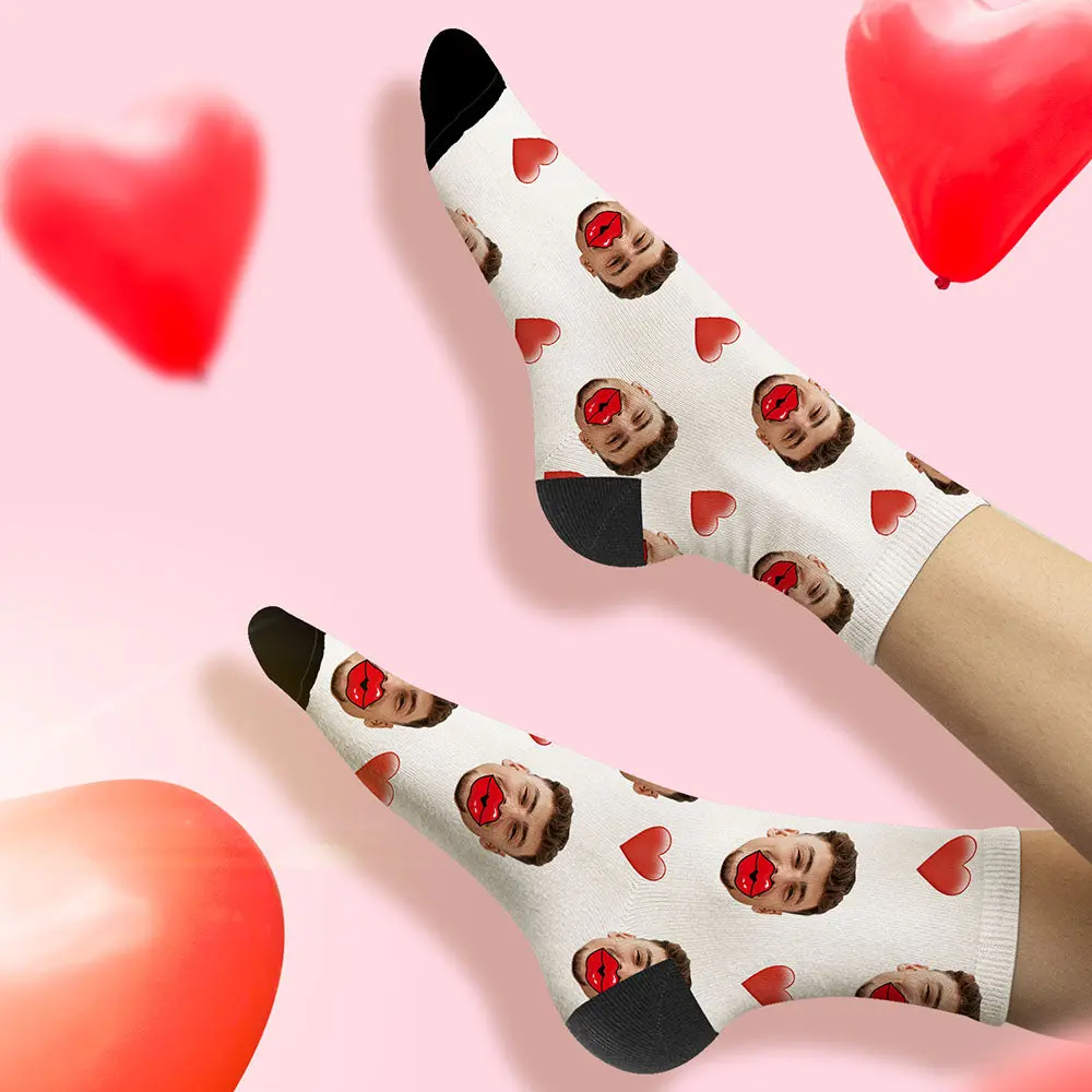 White socks with a repeating pattern of a man's face and red lips, interspersed with red hearts, set against a pink background with heart balloons.