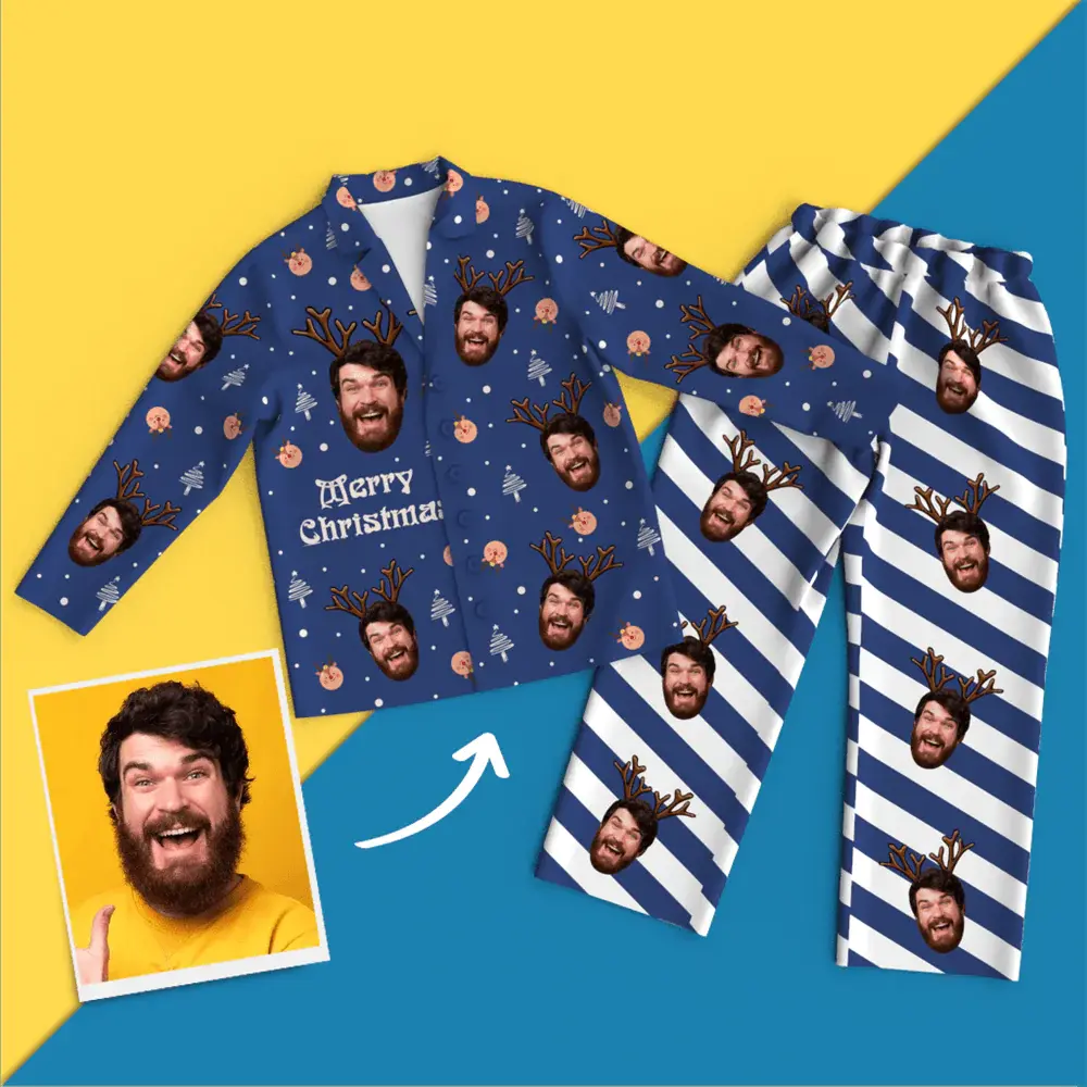 Blue Christmas pajama set with reindeer-face patterns and 'Merry Christmas' text, displayed on a yellow and blue stage. The striped pants feature the same reindeer heads.