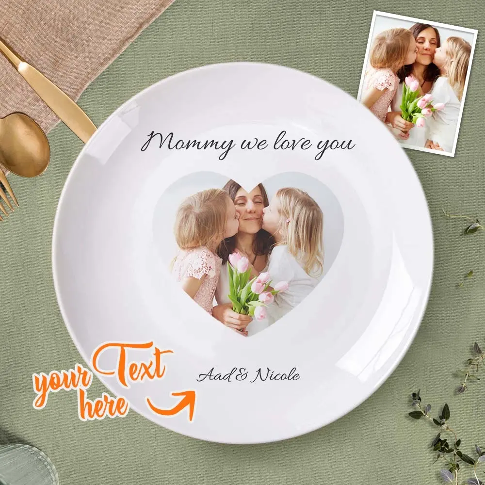 Personalized keepsake plate featuring a heart-shaped photo of a mother kissing two daughters, with the text 'Mommy we love you' and space for custom text (Ada & Nicole).