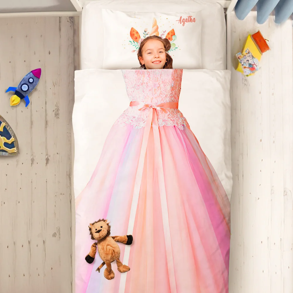 Girl smiles from a pink princess dress spread on a bed, with a plush lion at the foot and playful decorations nearby.