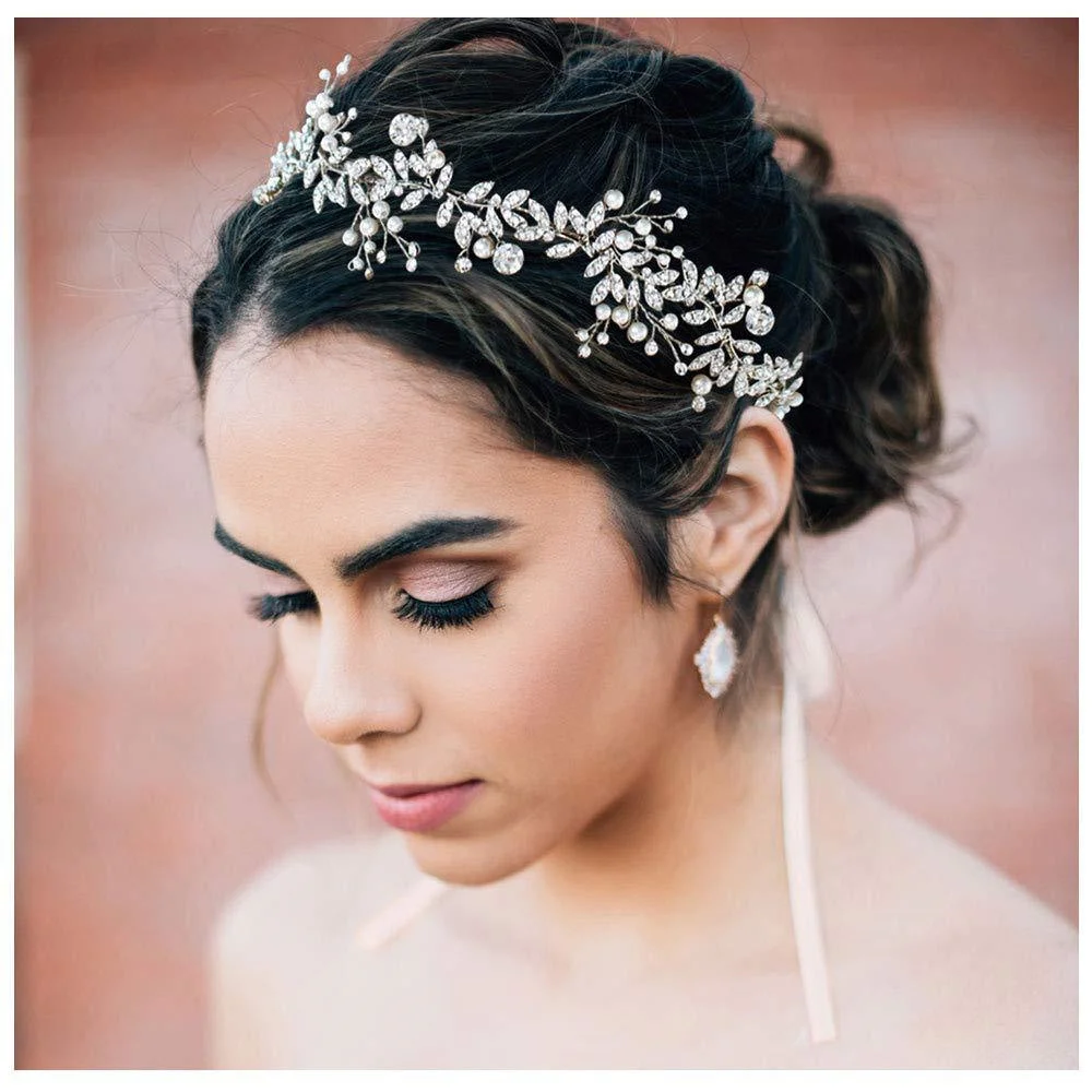 Bride with an ornate crystal headband in an updo, eyes closed, wearing drop earrings.