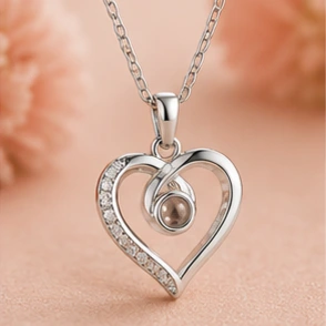 Silver heart pendant with a row of small diamonds along one arc and a central pearl, hanging from a delicate chain.