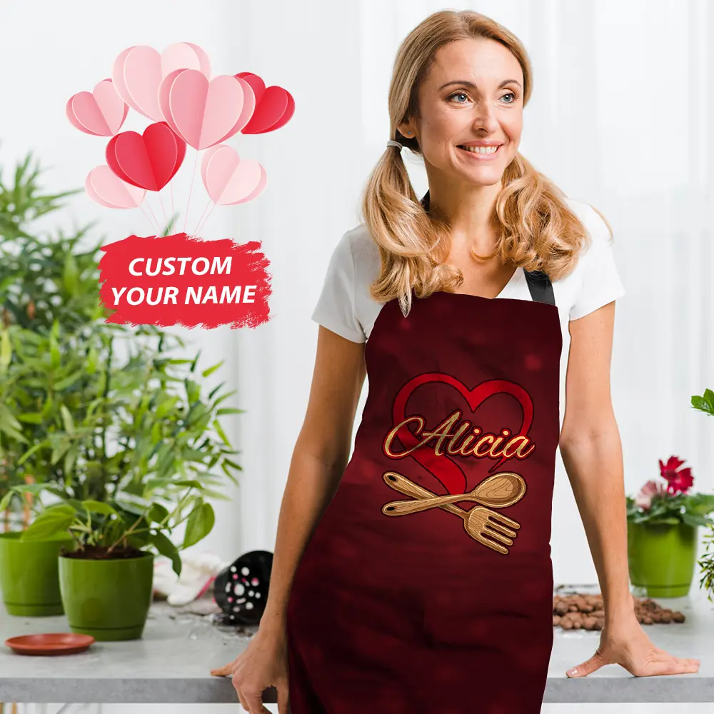 Smiling woman in a maroon customized apron with a heart and wooden utensils, name 'Alicia' shown on the front.