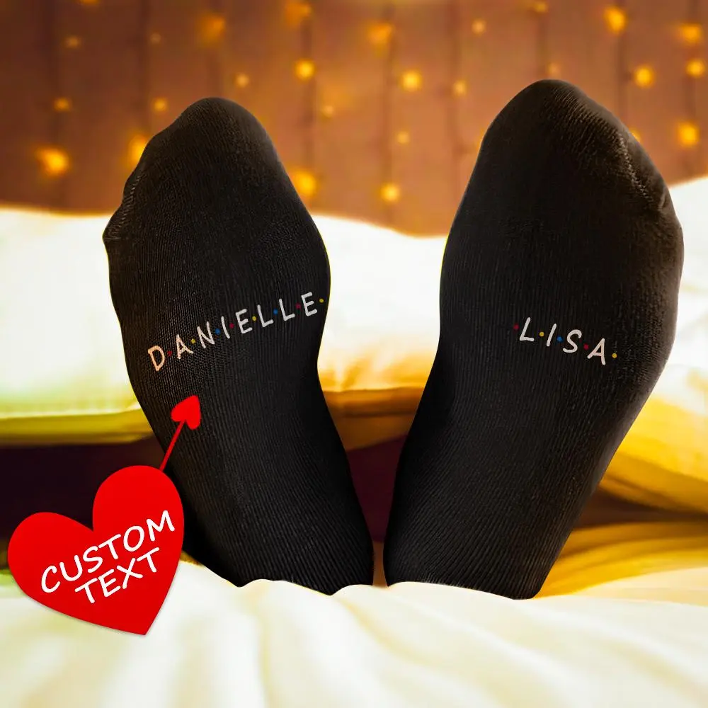Two feet in black custom-name socks reading DANIËLLE and LISA, with a red heart tag saying Custom Text (product-style).