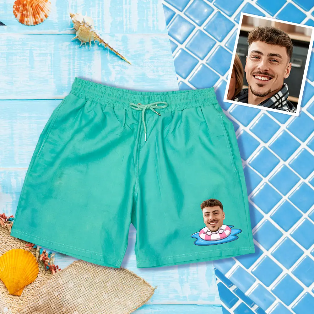 Turquoise swim shorts on a beach backdrop, with a photo of a man's head in a pink float on the lower right.