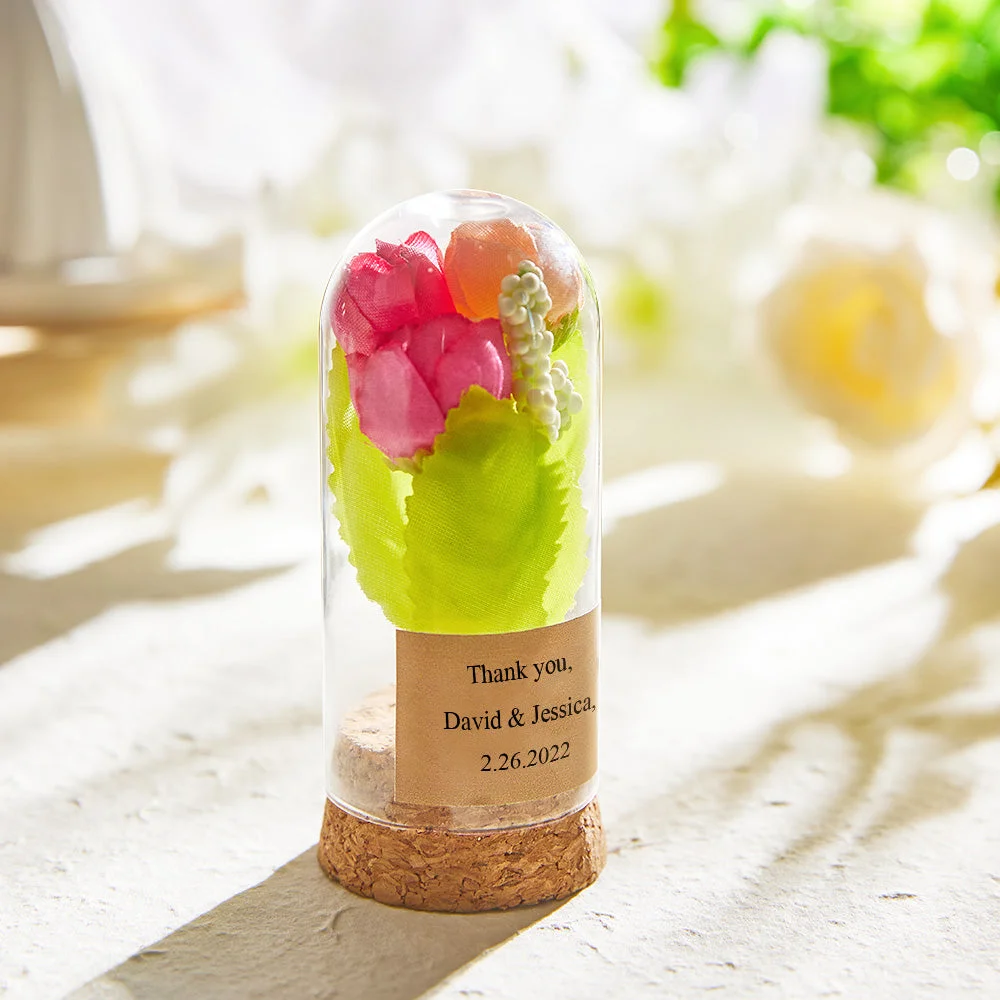 Glass dome with a cork base holding a colorful pressed-flower arrangement; label reads 'Thank you, David & Jessica, 2.26.2022'