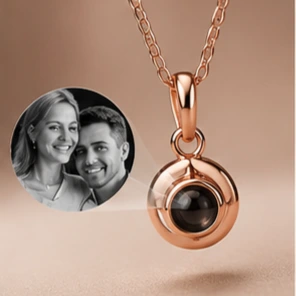 Rose gold circular locket necklace with a small black stone, featuring a round photo of a smiling couple encased beside the pendant.