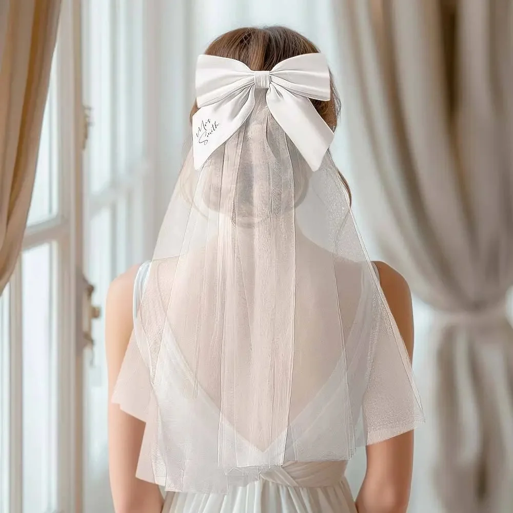 Bride seen from behind wearing a sheer wedding veil with a large white satin bow at the back.