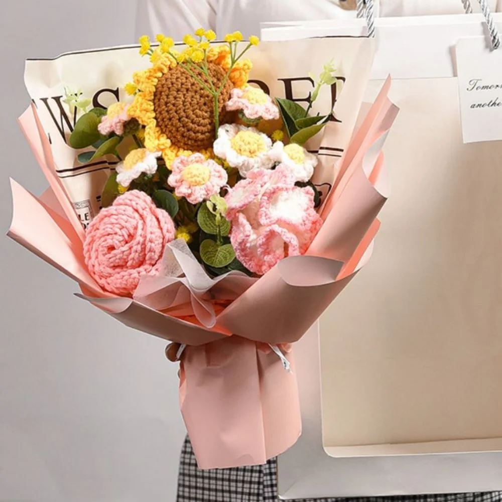 Pastel bouquet with pink crocheted flowers and yellow blooms wrapped in pink paper.