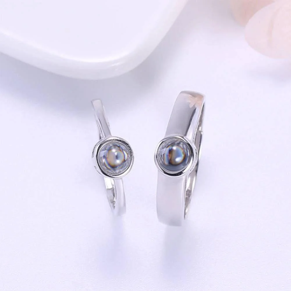 Pair of silver rings with round pearl centers, displayed on a pale surface.
