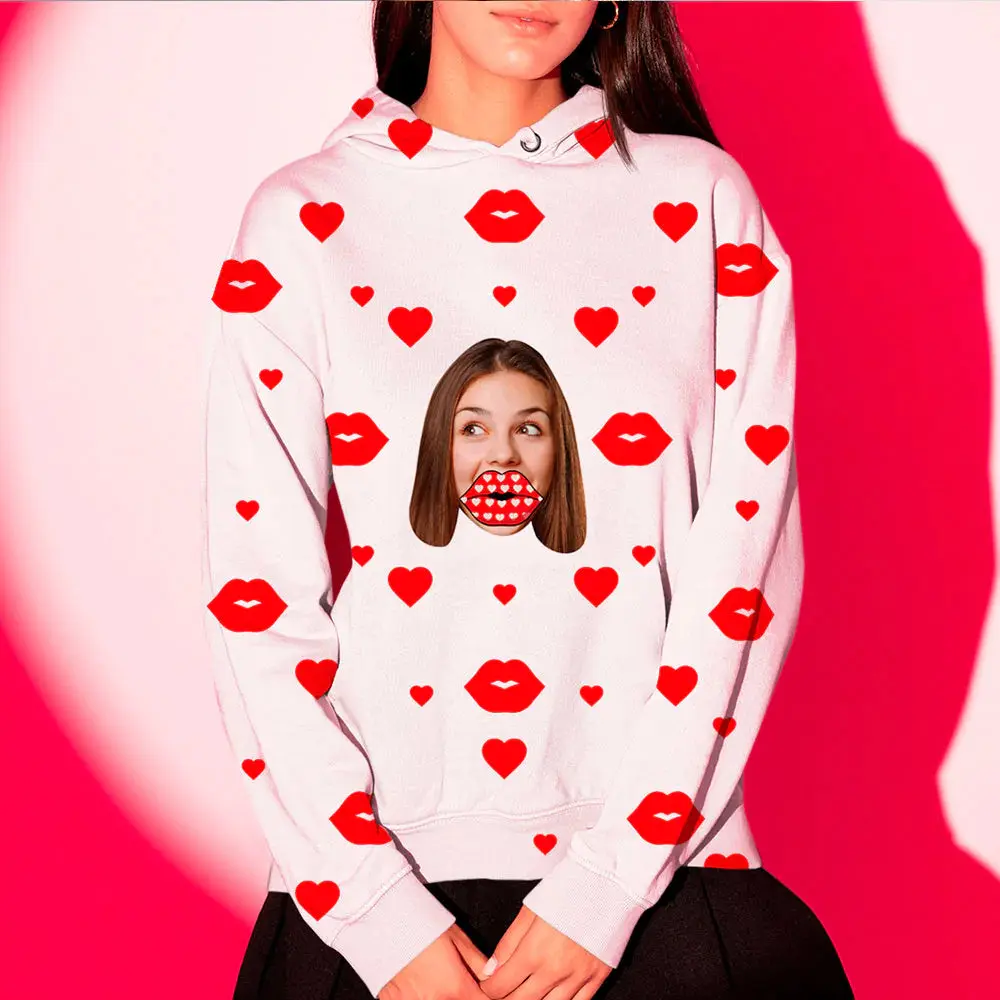 Person wearing a white hoodie covered in red hearts and red lip prints, with a cutout image of a woman's mouth on the chest area against a pink background.