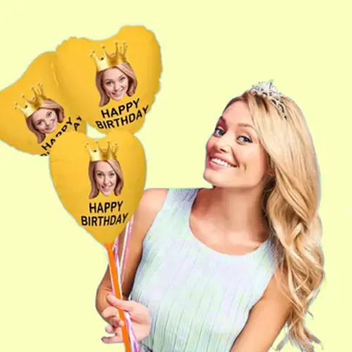 Smiling woman wearing a tiara, holding yellow balloons with 'Happy Birthday' and crown graphics.