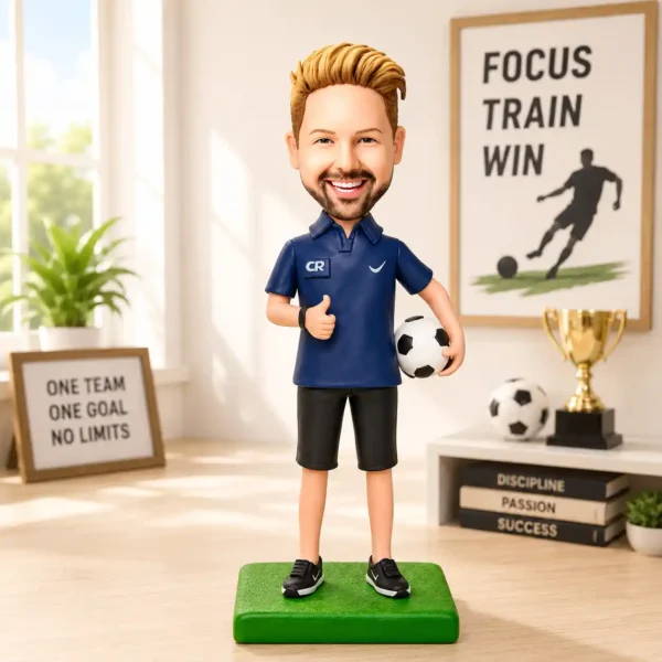 Smiling cartoon soccer coach figurine giving a thumbs up, holding a ball on a green base in a bright room with motivational posters and a trophy display.