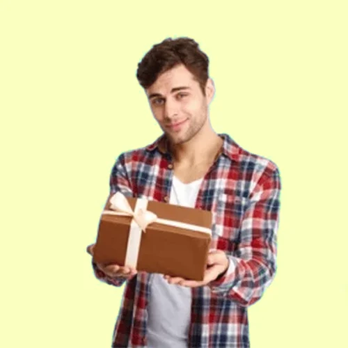Smiling man in a red plaid shirt holds a brown gift box with a white ribbon using both hands.