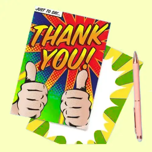 Colorful pop-art style 'THANK YOU!' card with two thumbs-up, on a pale yellow background beside a pink pen and decorative paper pieces.