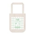Beige canvas tote bag with a light green gingham panel and a four-leaf-clover graphic on the front.
