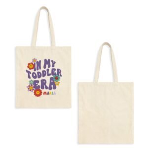 Two beige tote bags, one printed with a colorful 'On My Toddler Era' design and flowers; the other plain tote bag.