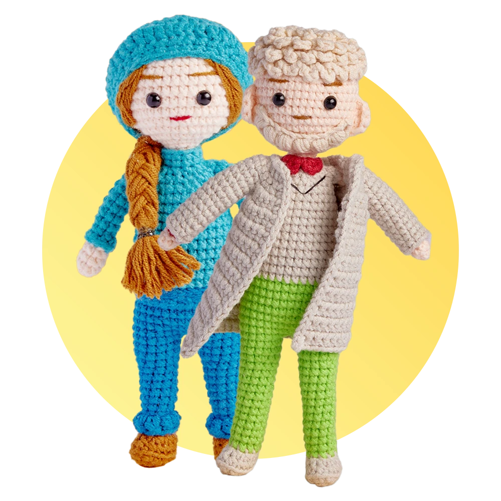 Two crocheted dolls posing together: a girl in blue with braided hair and an orange scarf and a boy in a beige coat with green pants, against a yellow circle backdrop.