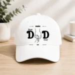 White baseball cap with a 'Best Dad Ever' graphic showing two hands clasped together.