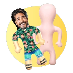 Smiling man in a shirt covered with faces poses with a pink practice dummy against a yellow circle.