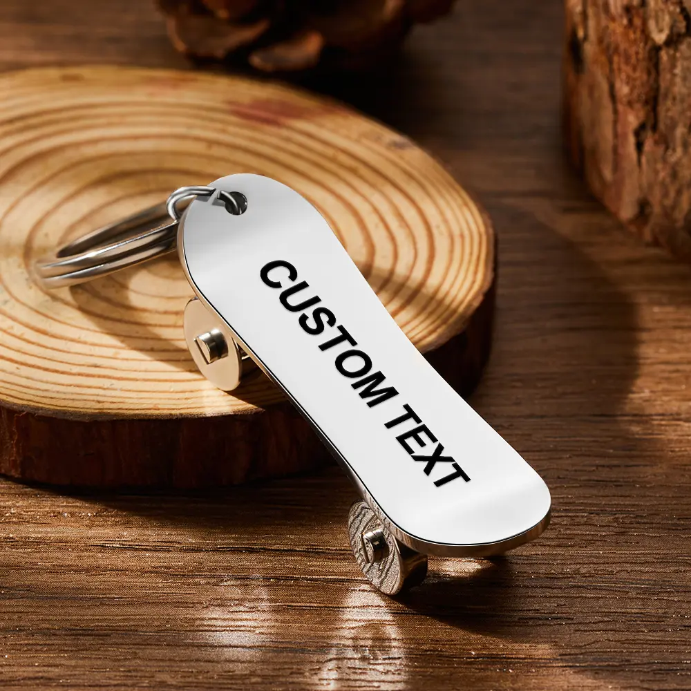 Shiny metal skateboard-shaped keychain with CUSTOM TEXT etched on the deck on a wooden surface.