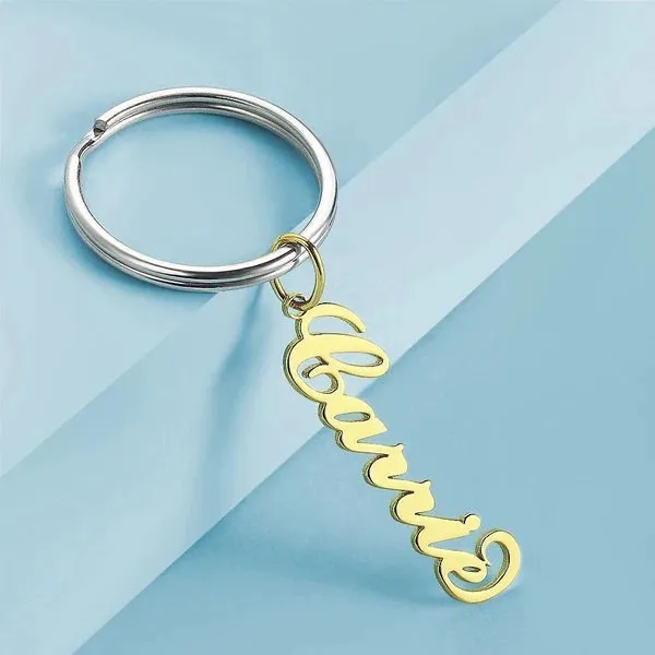 Gold cursive 'Bonjour' keychain attached to a silver ring on a pale blue background.
