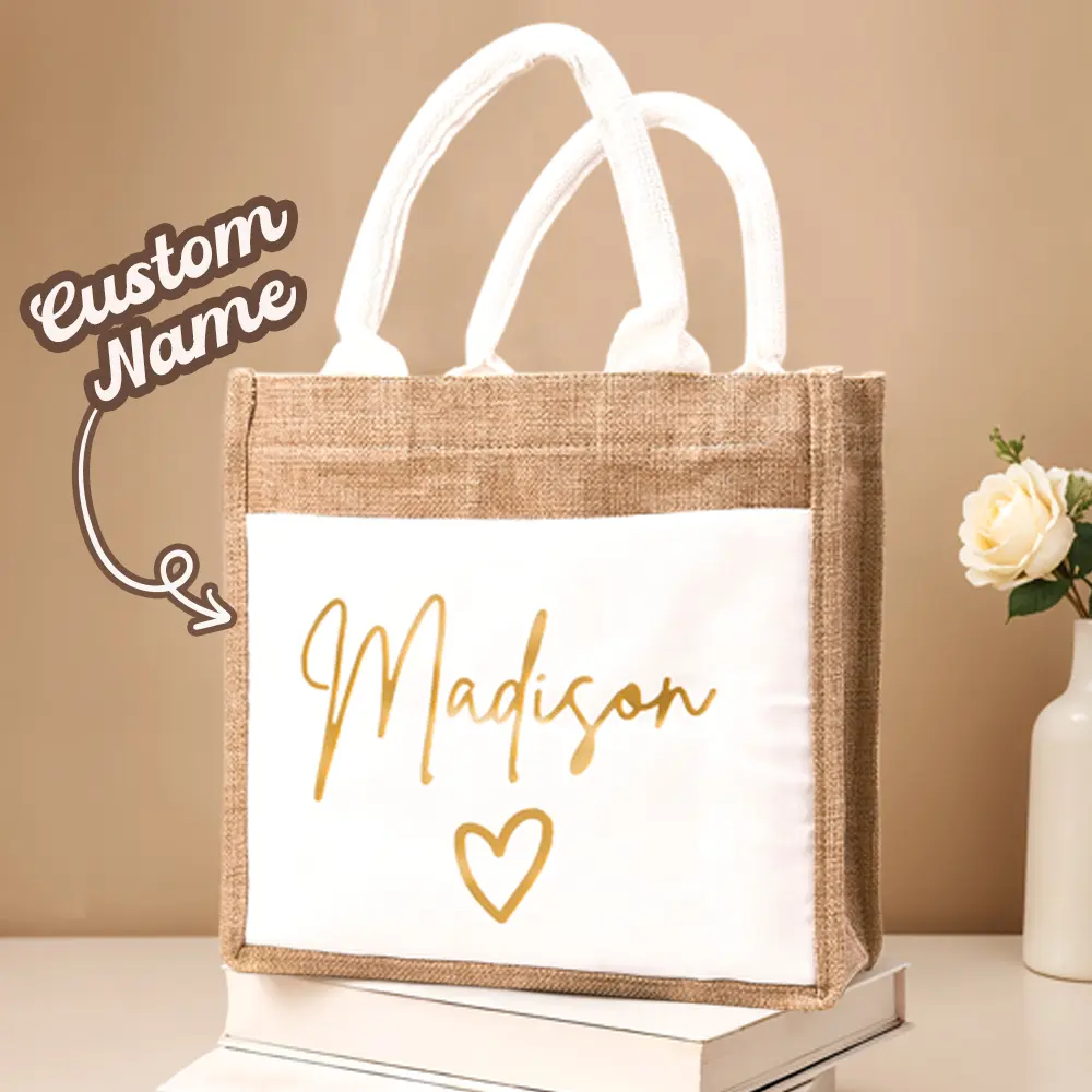 Beige burlap tote with a white front panel displaying the name 'Madison' in gold script and a heart below it.