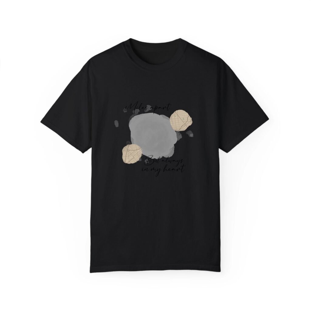 Black t-shirt with abstract gray paint splatters and beige map-pattern circles, plus subtle handwritten text.